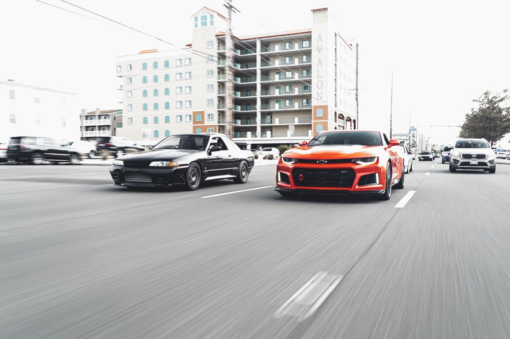 Which car is older, the black car or the red car?